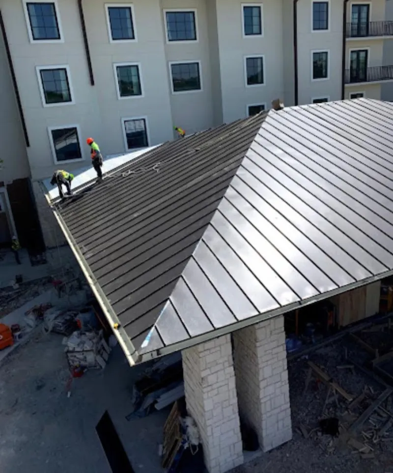 Crew installing standing seam metal roof panels on a commercial project in Cedarhurst